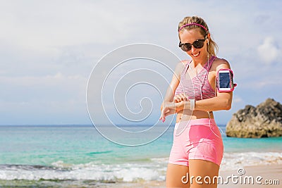 Woman using wearable tech while exercising outdoors Stock Photo