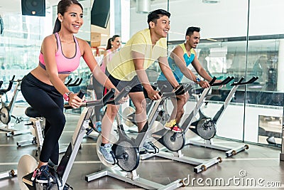 Fit women burning calories during indoor cycling class in a fitness club Stock Photo