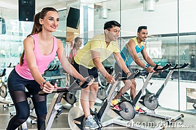 Fit women burning calories during indoor cycling class Stock Photo