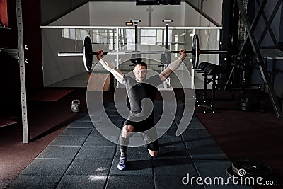 Fit young athlete lifting the barbell in gym. Gym training. Full body length portrait. Stock Photo