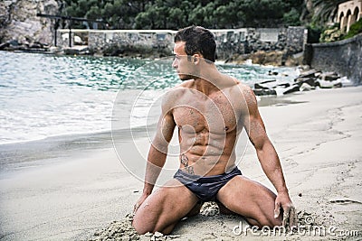 Fit young bodybuilder in bathing suit on the beach Stock Photo