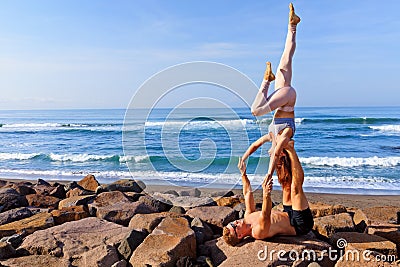 Fit young couple doing acro yoga exercise at sea beach Stock Photo