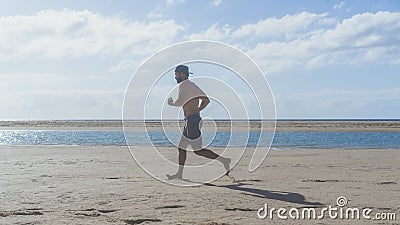 Fit young male sport fitness model exercising in full body in summer. Handsome strong caucasian man training ocean beach. Stock Photo