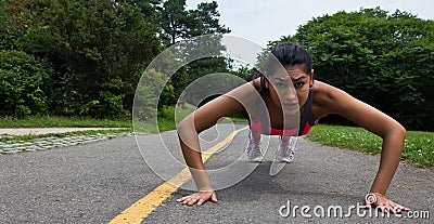 Fit young woman doing push-ups outdoors Stock Photo
