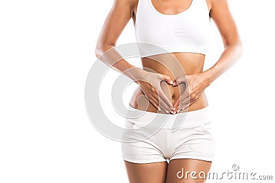Fit young woman holding a heart over her abdomen, on white background Stock Photo