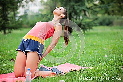 Fit young woman practicing yoga in a city park, doing Tibetan rite number three Stock Photo