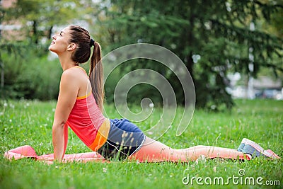 Fit young woman practicing yoga in city park Stock Photo