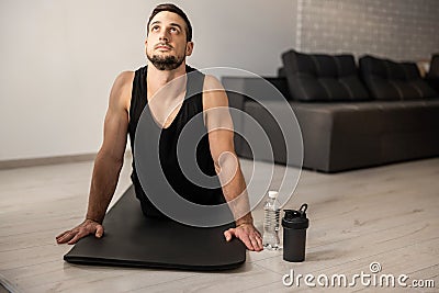 Fitn man meditating while doing cobra pose in living room. Indoor shot of handsome young man practicing yoga. Morning Stock Photo