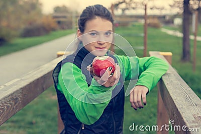 Fitnes trainer offering an apple at outdoor gym. Stock Photo