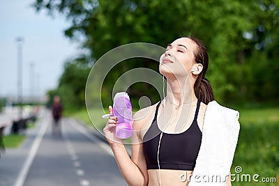 Fitness asian woman with bottle of water and towel after running training in summer park Stock Photo