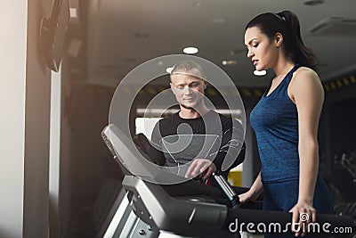 Fitness coach helps woman on elliptical trainer Stock Photo