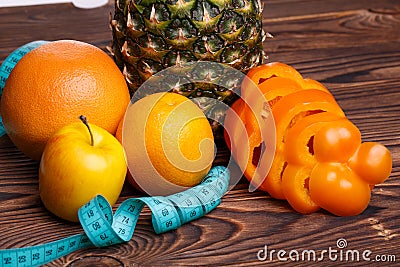 Fitness concept with pineapple, oranges, apples, sweet pepper and measuring tape Stock Photo