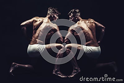 Fitness dieting and flexibility in acrobatics. Twins men with muscular body in pose. Circus gymnasts at pilates or yoga Stock Photo