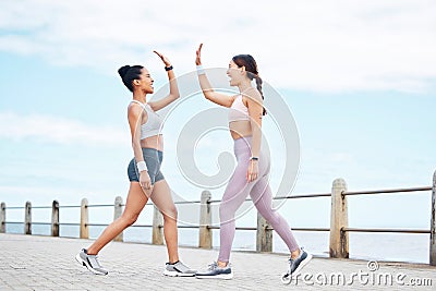 Fitness, friendship and high five, women on running path at the ocean for motivation, support and friends to workout Stock Photo