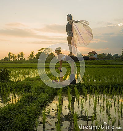 Fitness and friendship - young happy and attractive group of friends doing acro yoga workout in balance on rice field with Stock Photo
