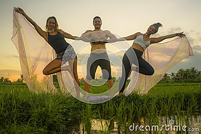 Fitness and friendship - young happy and attractive group of friends doing acro yoga workout playful on rice field with beautiful Stock Photo