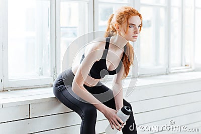 Fitness girl resting holding water bottle at the gym Stock Photo