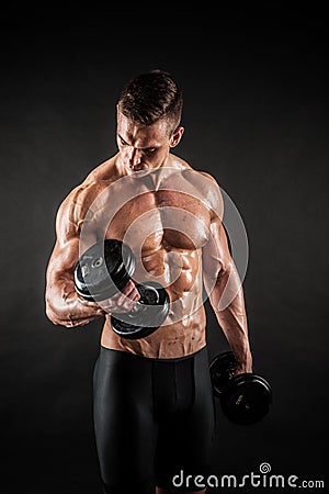 Fitness in gym, sport and healthy lifestyle concept. Handsome athletic man showing his trained body on black background Stock Photo