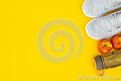 Fitness and healthy active lifestyle background concept. Training sneakers, water bottle and apples on yellow background. Top Stock Photo