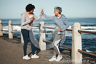 Fitness, high five and senior women by ocean for healthy lifestyle, wellness and cardio on promenade. Sports, friends Stock Photo