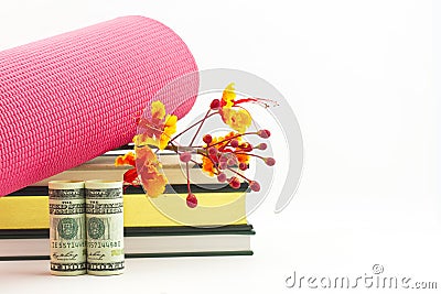 Fitness industry success symbolized in yoga mat, books, flowers, and currency Stock Photo