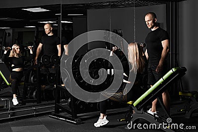 Fitness instructor conducts personal training for a girl with dumbbell in front of the mirror Stock Photo