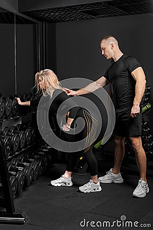 Fitness instructor conducts training for a girl with dumbbell in front of the mirror Stock Photo