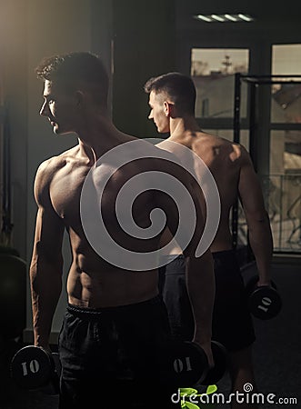 Fitness instructor. Man with torso, muscular macho and his reflexion in mirror background. Sport and gym concept Stock Photo