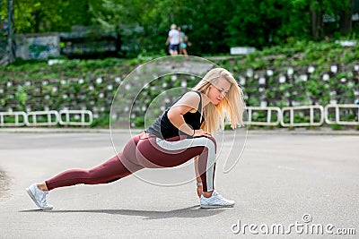 Fitness lifestyle. Young woman doing lunges to the side. Workout at the stadium. Healthy life concept. Horizontal photo Stock Photo