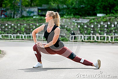 Fitness lifestyle. Young woman warming up before training doing exercises to stretch her muscles and joints. Workout at the Stock Photo