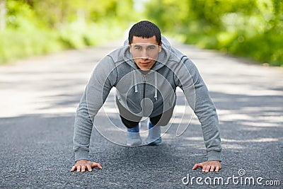 Fitness man exercising push ups, outdoor. Muscular male cross-training on city park Stock Photo