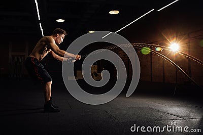 Fitness man workout with battle ropes at gym. training exercise fitted body in club. Torso. Stock Photo