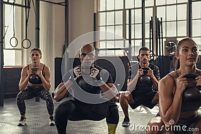 Fitness people squatting with kettlebell Stock Photo