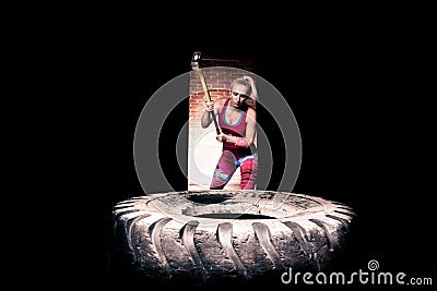 Fitness sledge hammer woman workout at gym.Sledgehammer tire hits woman workout at gym with hammer and tractor tire. Stock Photo