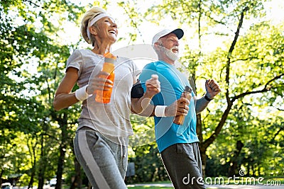 Fitness, sport, people, exercising and lifestyle concept - senior couple running Stock Photo