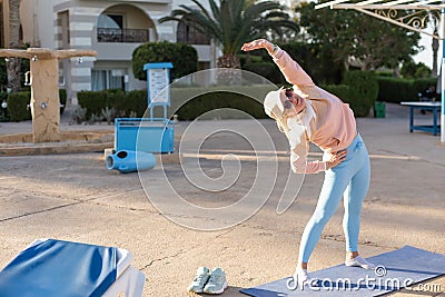 fitness, sport, people and healthy lifestyle concept - woman making yoga in lord of the dance pose on mat over beach and Stock Photo