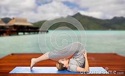 Woman making yoga in plow pose on mat outdoors Stock Photo