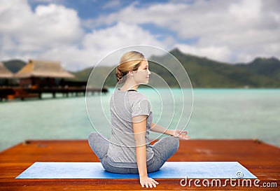 Woman making yoga in twist pose on mat outdoors Stock Photo