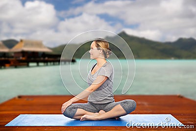 Woman making yoga in twist pose on mat outdoors Stock Photo