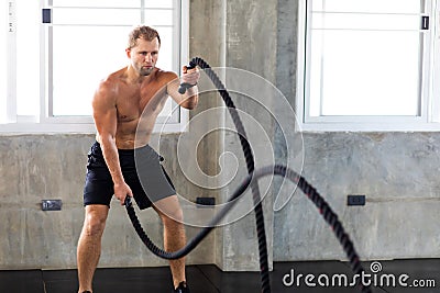 Fitness and sports man training with battle rope in cross fit gym. Fitness Healthy lifestye and workout at gym concept Stock Photo