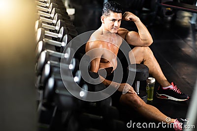 Fitness and sportsman taking a break after training lifting dumbbell sitting at the gym . Fitness Healthy lifestye and workout at Stock Photo