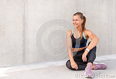 Fitness sporty woman is sitting and having a break after running early in the morning city at sunrise Stock Photo