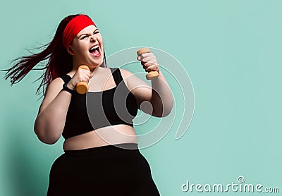 Fitness spring diet weight loss concept. Screaming loud plus-size overweight woman does exercises with weights dumbbell Stock Photo