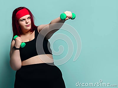 Fitness spring diet weight loss concept. Plus-size overweight woman does punches with dumbbells holding arm outstretched Stock Photo