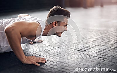 Fitness starts with that first push. a young man doing pushups in a gym. Stock Photo