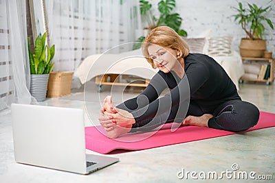 Fitness training online, senior woman at home with laptop Stock Photo