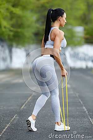 Fitness woman doing deadlift exercise for glutes with resistance band outdoors. Athletic girl working out Stock Photo