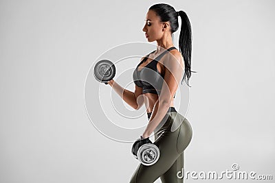 Fitness woman doing exercise for biceps on gray background. Muscular woman workout with dumbbells Stock Photo