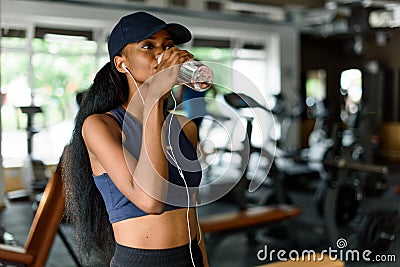 Fitness woman exercising in gym and drinking water from bottle. Female model with muscular fit slim body. Stock Photo