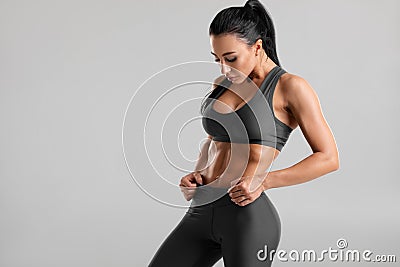 Fitness woman showing abs and flat belly, on gray background. Beautiful athletic girl, shaped abdominal Stock Photo